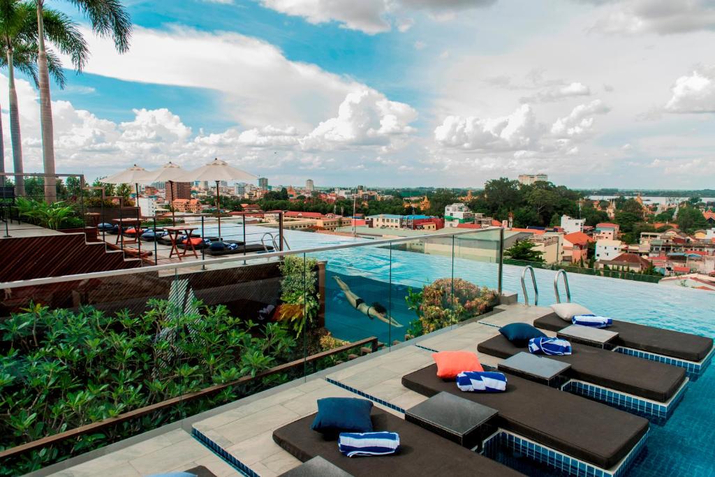 widok na basen w ośrodku ze stołami i krzesłami w obiekcie Aquarius Hotel and Urban Resort w mieście Phnom Penh