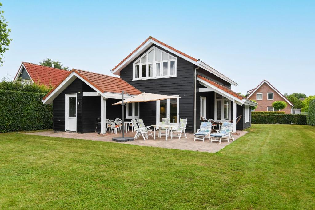 Cette maison noire dispose d'une terrasse avec des chaises et des tables. dans l'établissement The Black House - Luxurious Holiday Villa Zeewolde, à Zeewolde