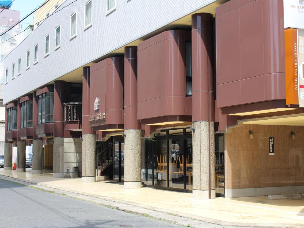 ein Gebäude mit roten Säulen auf einer Stadtstraße in der Unterkunft Hotel Trend Mito in Mito