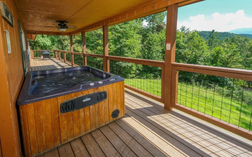 a large screened porch with a hot tub on the deck at Cozy Bear Camp in Sevierville