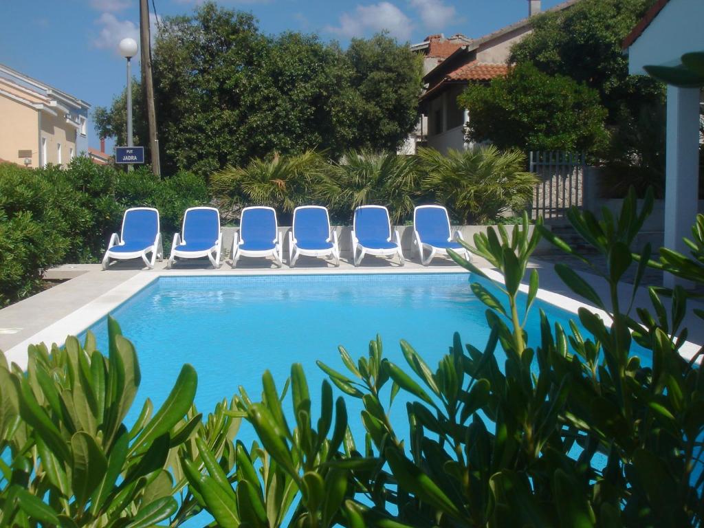 a swimming pool with blue chairs and plants at Villa Laurus I in Kožino