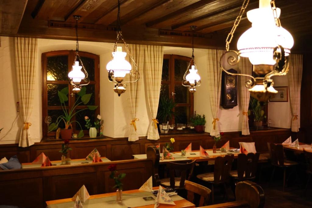 a dining room with tables and chairs and lights at Landgasthof Hotel Zum Roß Dorfgütingen in Feuchtwangen
