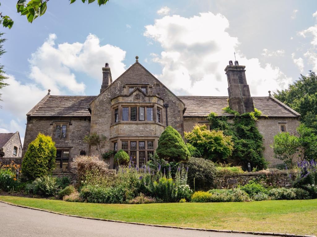 an old stone house with a garden in front of it at YHA Hartington Hall in Hartington
