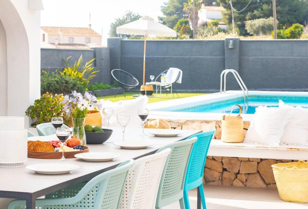 a table and chairs with food and drinks and a pool at Finca Tossalet. Piscina privada y barbacoa in Benissa