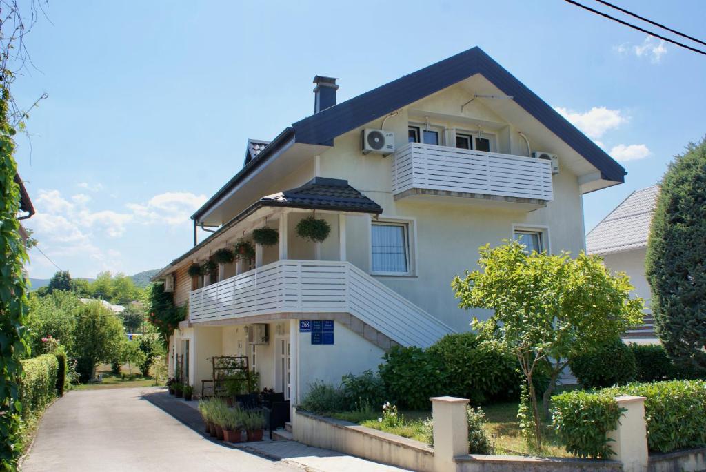 a white house with a porch and a balcony at House Magdic Plitvice in Grabovac
