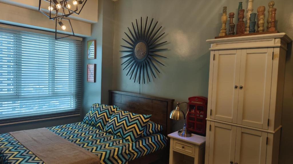 a bedroom with a bed and a clock on the wall at Studio Premier Suite Makatii by Christine Suites PH in Manila