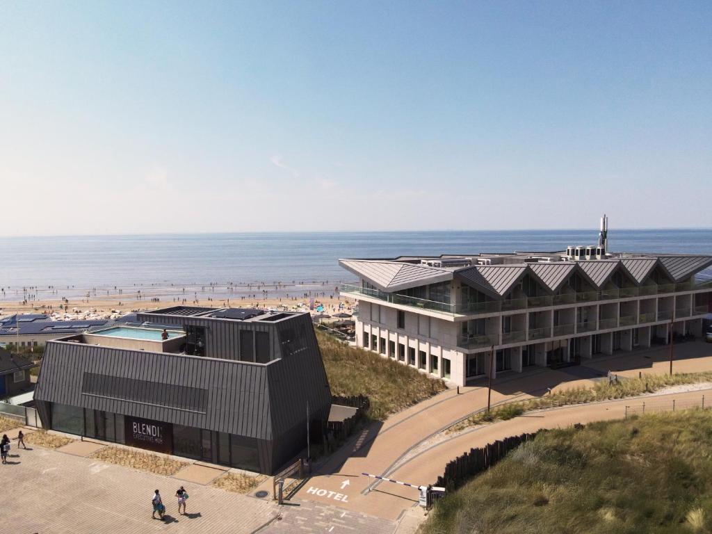 a building on the beach with the ocean in the background at Boutique Hotel Blendin Bloemendaal aan Zee in Bloemendaal Aan Zee