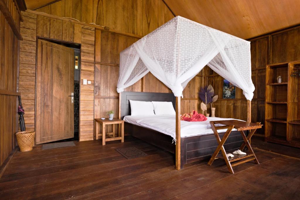 une chambre avec un lit à baldaquin en filet dans l'établissement Lavana Dive & Nature Resort, à Unauna