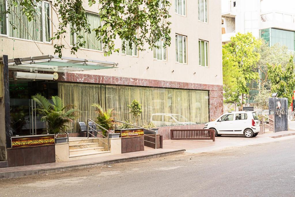 un coche blanco estacionado frente a un edificio en Super Inn Armoise Hotel en Ahmedabad