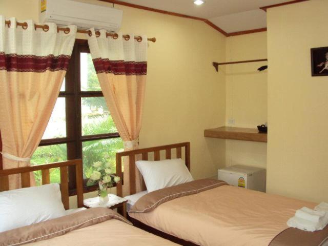 a bedroom with two beds and a window at Baanphuthadol in Mae Hong Son