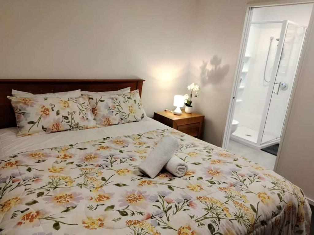 a bedroom with a bed with a flowery bedspread at Cosy Sunny Bedroom Close to Airport in Christchurch