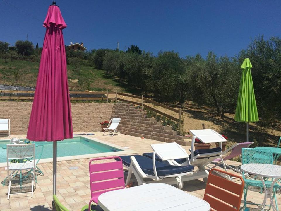 a group of chairs and umbrellas next to a pool at Fattoria Riomoro in Colonnella
