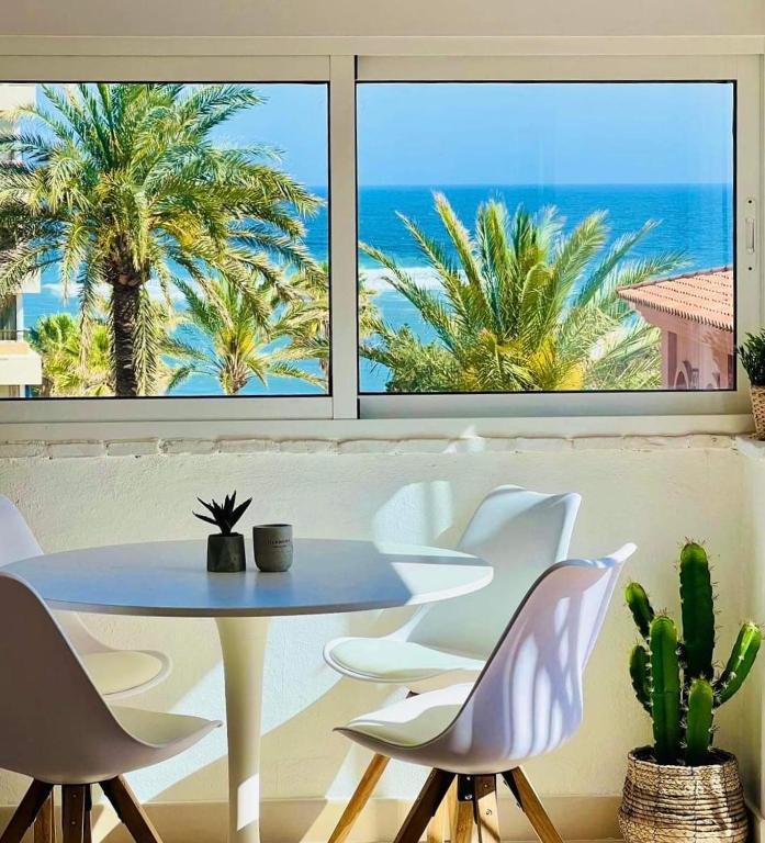 a table and chairs in a room with a view of the ocean at Penthouse - Beach - Sea View - Pool - 40 sqm Private Terrace - One Bedroom - Sleeping Alcove in Benalmádena