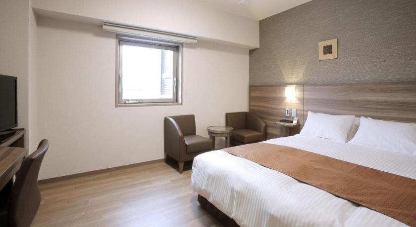 a hotel room with a large bed and a chair at Hotel Sunoak Kashiwanoha in Funato