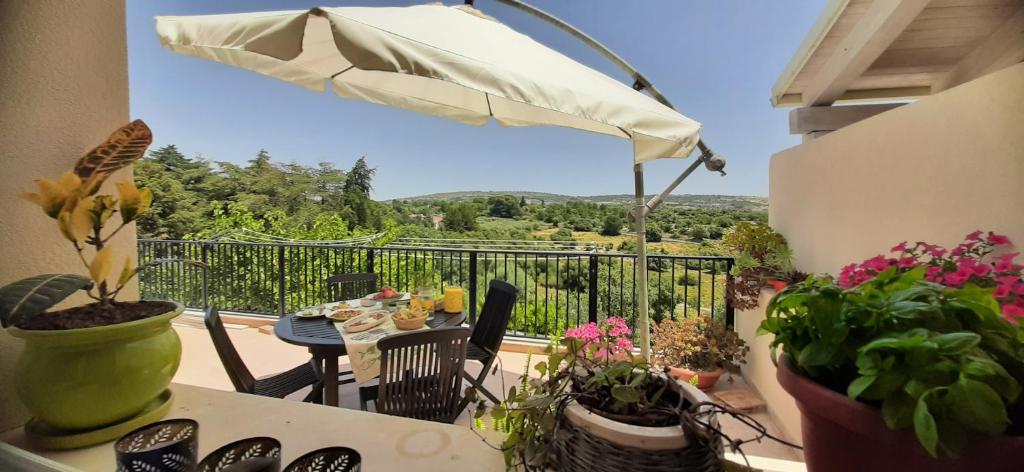 a balcony with a table with plants and an umbrella at Alabianca in Villa Vela