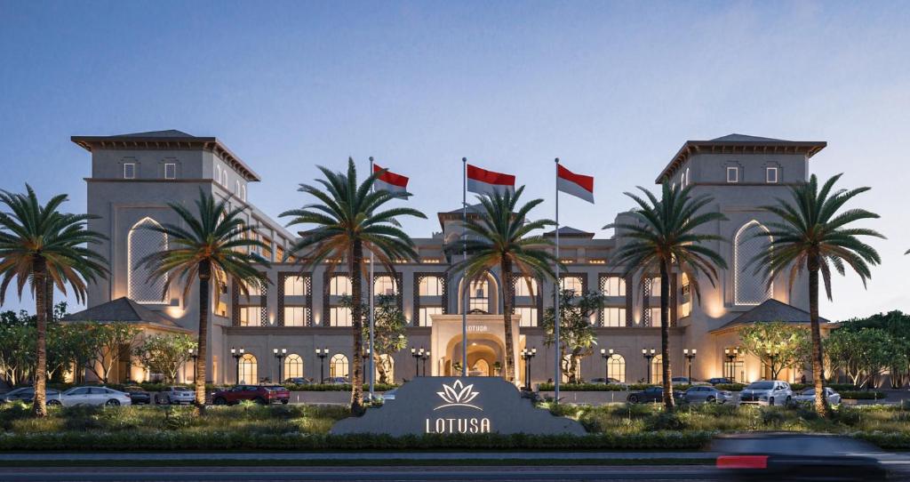 a hotel with palm trees in front of a building at Lotusa Batulicin by Swiss-Belhotel in Mantaak