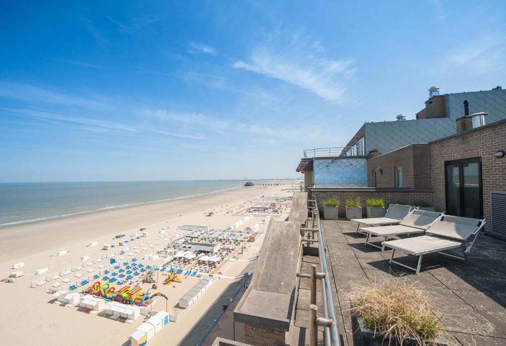 - une plage avec des chaises et des parasols et l'océan dans l'établissement C-Hotels Helios, à Blankenberge