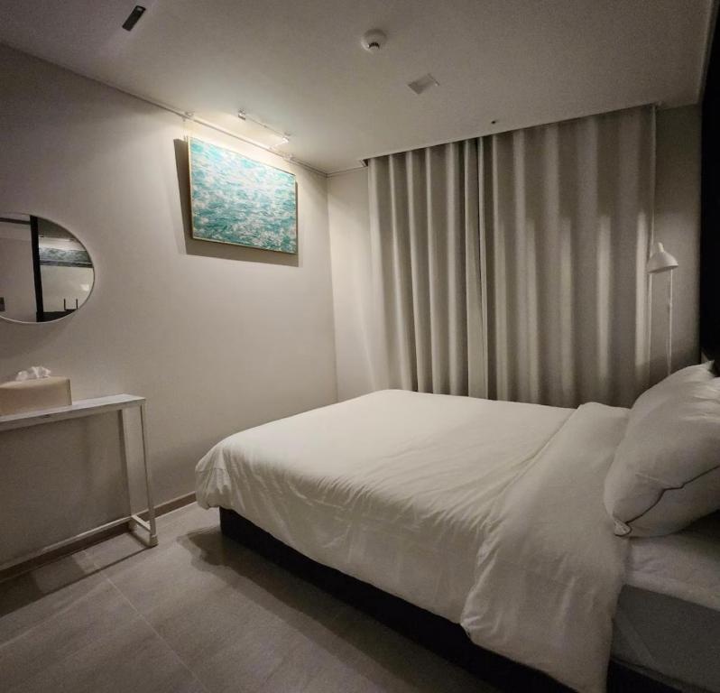 ein Schlafzimmer mit einem weißen Bett und einem Waschbecken in der Unterkunft Ocean GYM n Spa, free parking in Busan