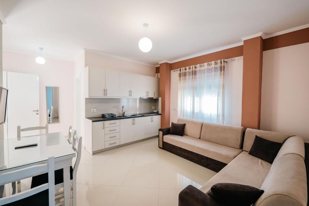 a living room with a couch and a kitchen at Fjori's Apartments in Sarandë