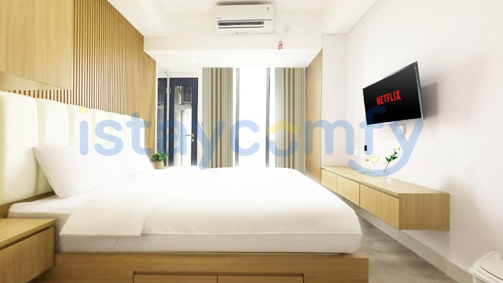 a bedroom with a bed and a tv on a wall at Studio Pollux Habibie B1617 City View in Batam Center