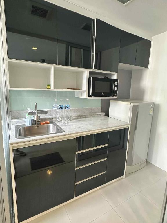 una cocina con fregadero y microondas en The Room Sukhumvit 64 Punnawithi, en Phra Khanong