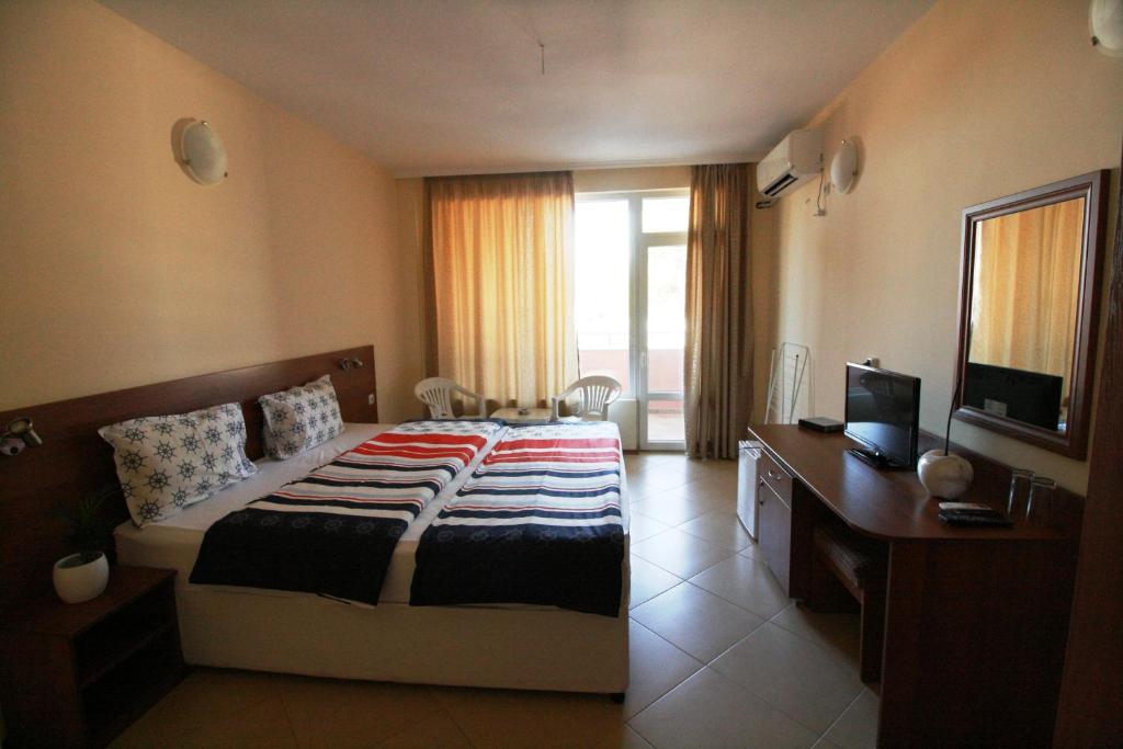 a bedroom with a bed and a desk and a television at Hotel Marant in Sozopol