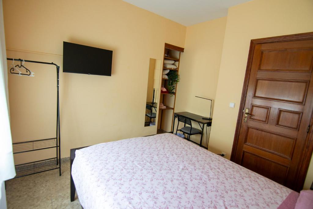 a bedroom with a bed and a tv and a door at Cal Kim in Martorell
