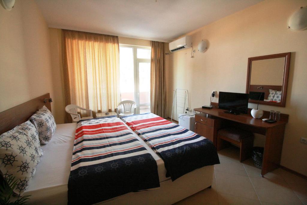 a bedroom with a bed and a desk and a mirror at Hotel Marant in Sozopol
