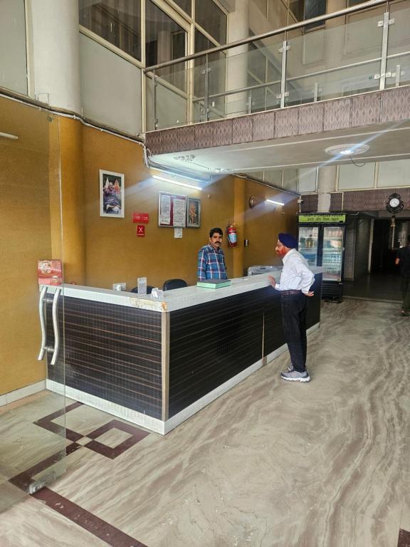 dos personas de pie en un mostrador en un edificio en Hotel Amber Palace, en Dehradun
