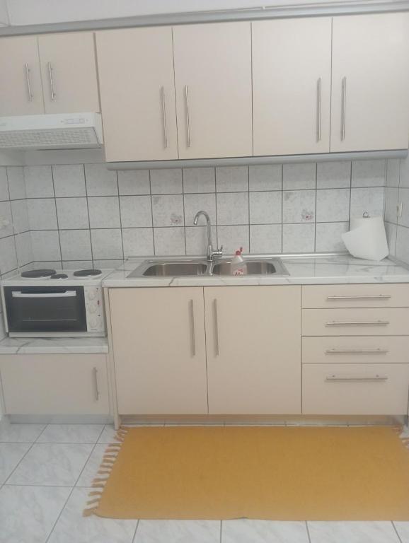 a kitchen with white cabinets and a sink at Ευρυχωρο ισόγειο διαμέρισμα in Moláoi
