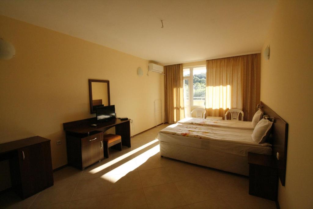 a bedroom with a bed and a desk and a window at Hotel Marant in Sozopol