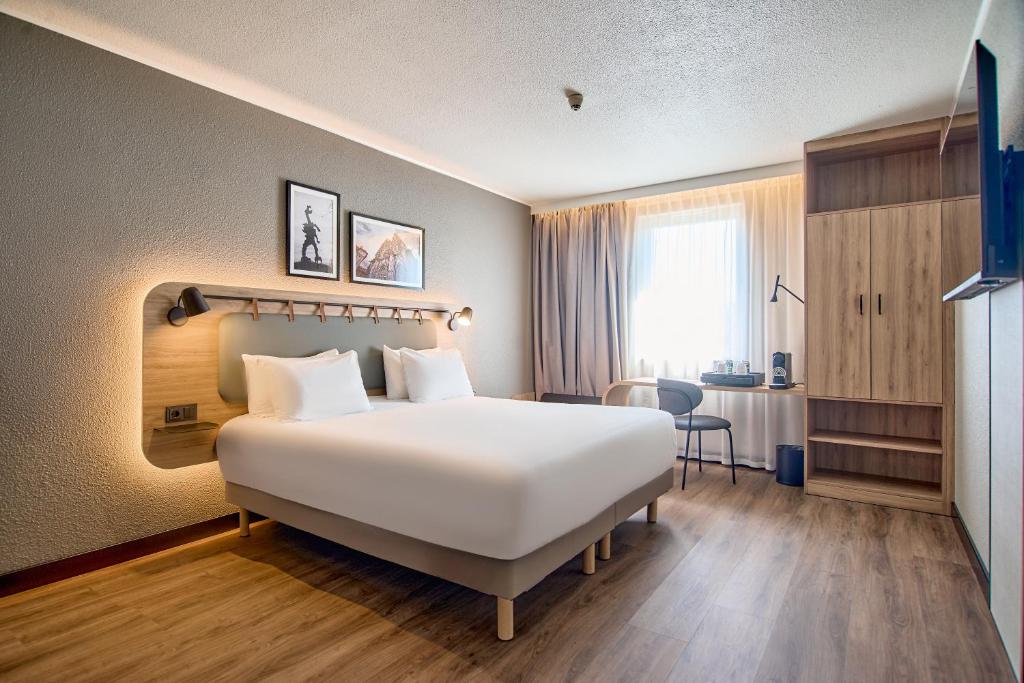 Una habitación de hotel con una gran cama blanca y un escritorio. en CAMPANILE PRIME Krakow Old Town, en Cracovia