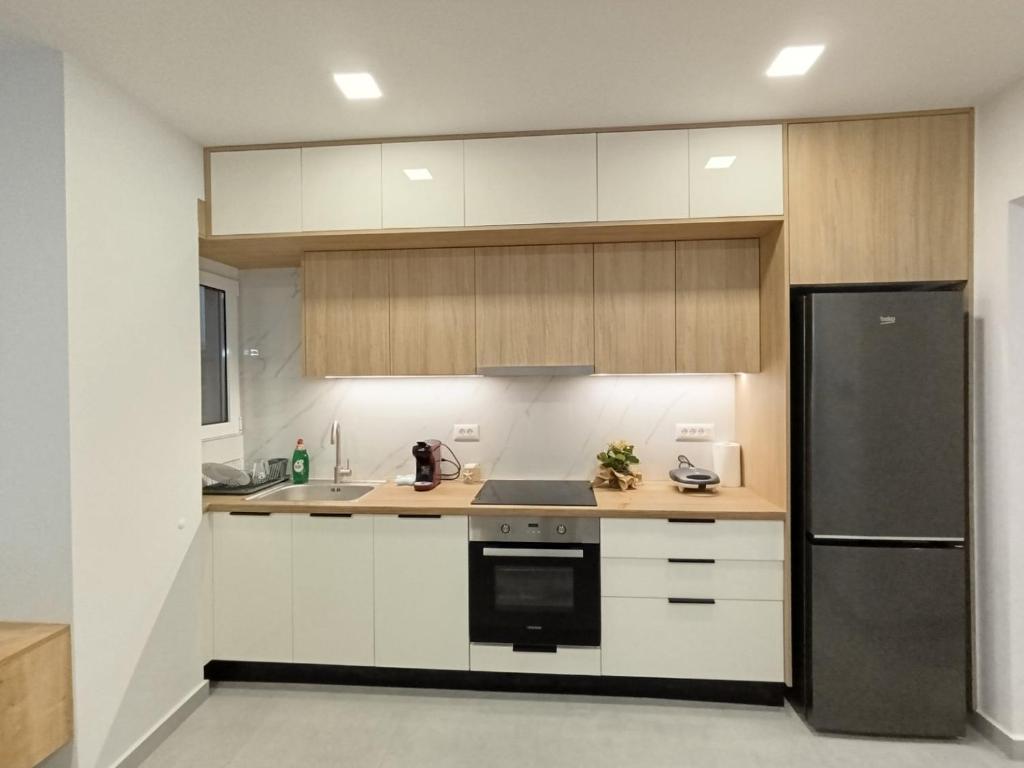 Una cocina con gabinetes blancos y un refrigerador negro. en MC Luxury Living, en La Canea