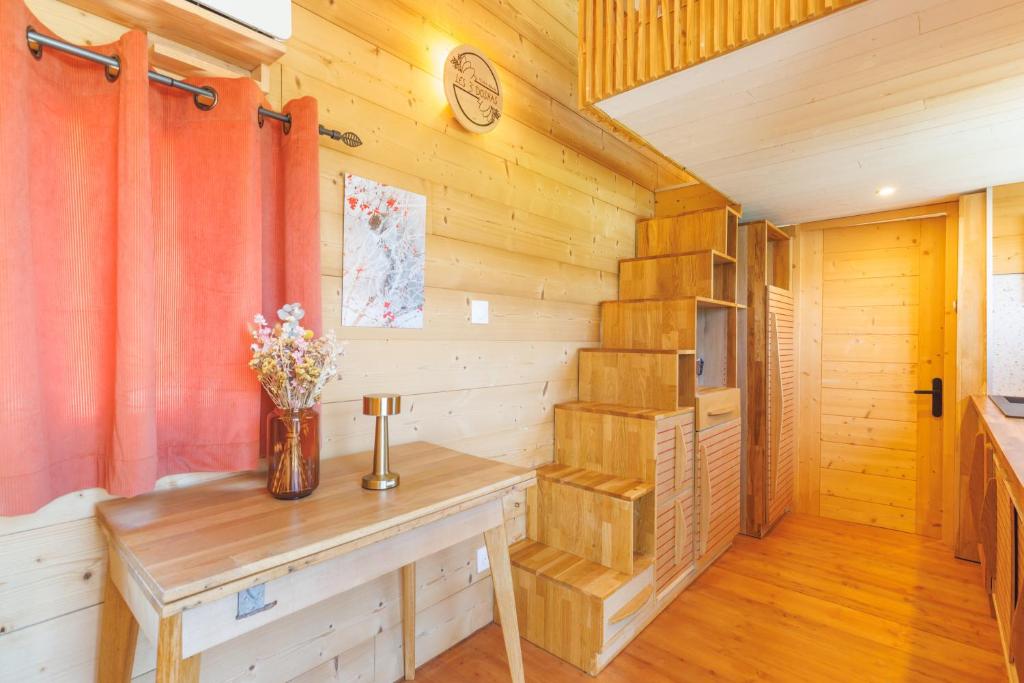 Ce chalet en bois comprend une table et des fleurs. dans l'établissement Tiny house Pitta, à Les Alliés