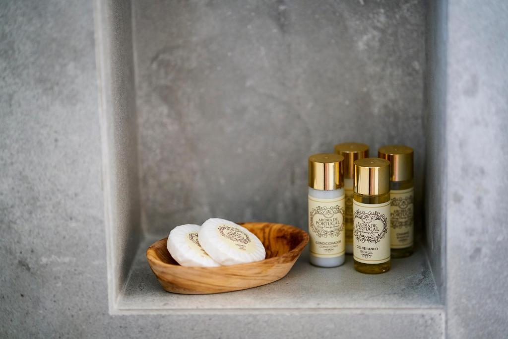 a shelf with three bottles of essential oils and a basket at Sparrow Sintra Nest in Sintra