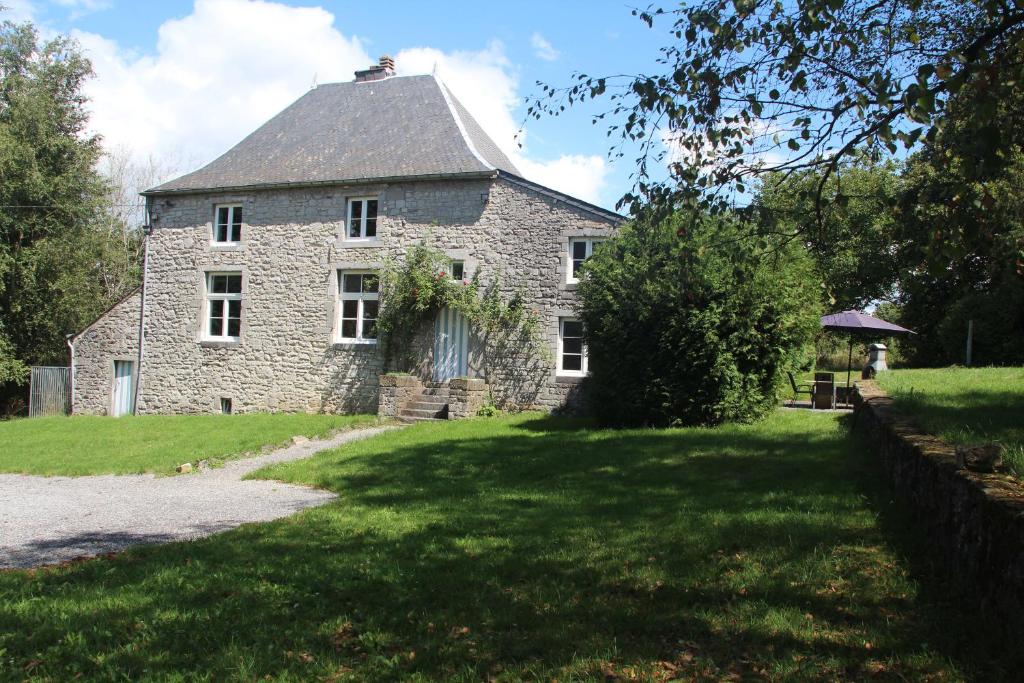 una vieja casa de piedra en un césped verde en Ferme Aux Moines en Humain