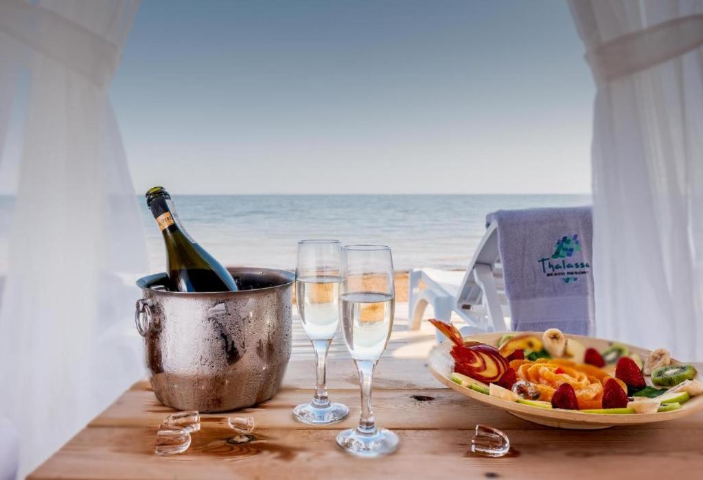 a table with two glasses of wine and a plate of food at Exclusive Apartments in Thalassa Beach Resort in Vokolidha