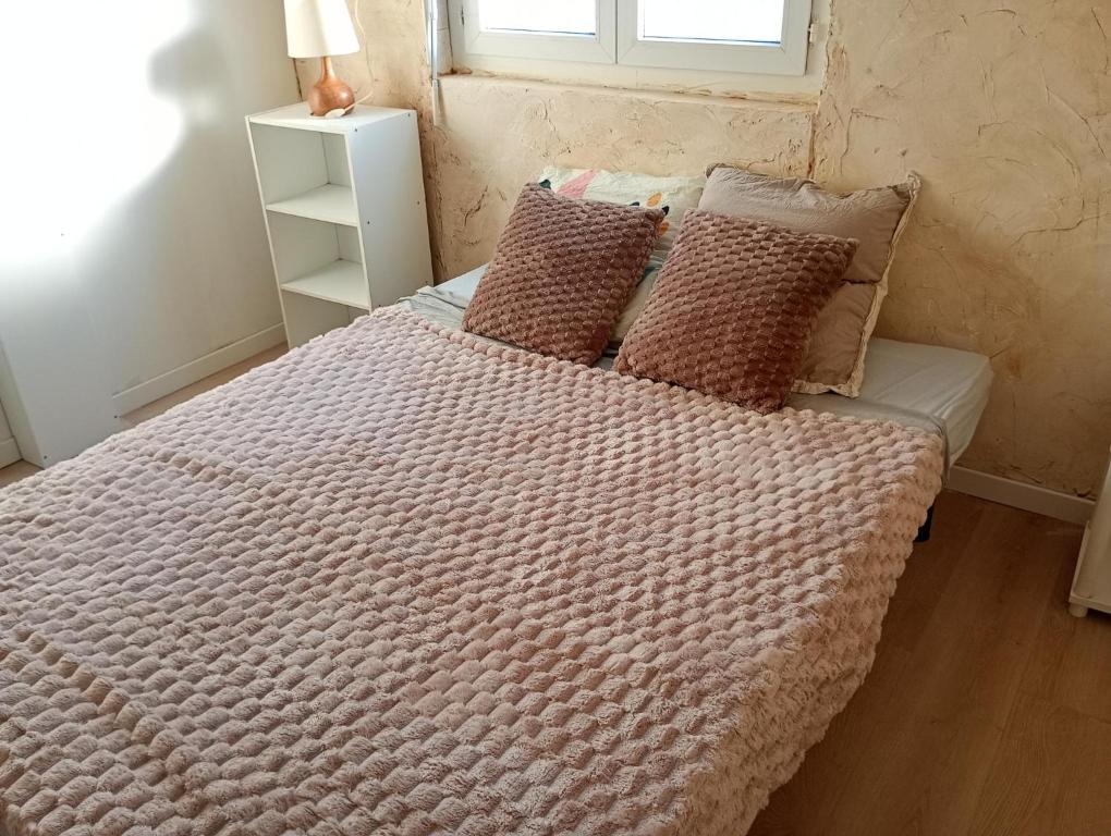 una camera da letto con un letto con una coperta e cuscini di Le clos joli ad Argelès-sur-Mer