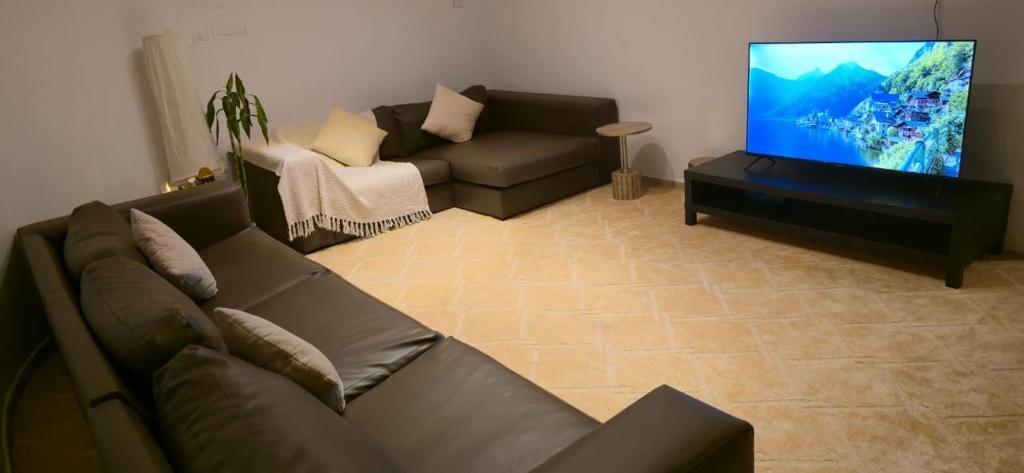 a living room with a couch and a flat screen tv at بيت عز اقامة راقية in Aţ Ţunḑubāwī