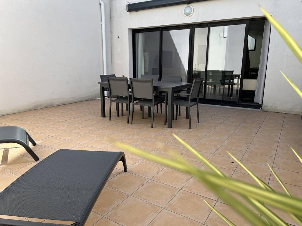 un patio avec une table, des chaises et des fenêtres dans l'établissement Maison 4 pièces St Pierre d'Oléron, lumineux et rénové - FR-1-246A-137, à Saint-Pierre-dʼOléron