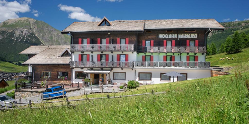 a large house on a hill with a mountain at Hotel Teola in Livigno
