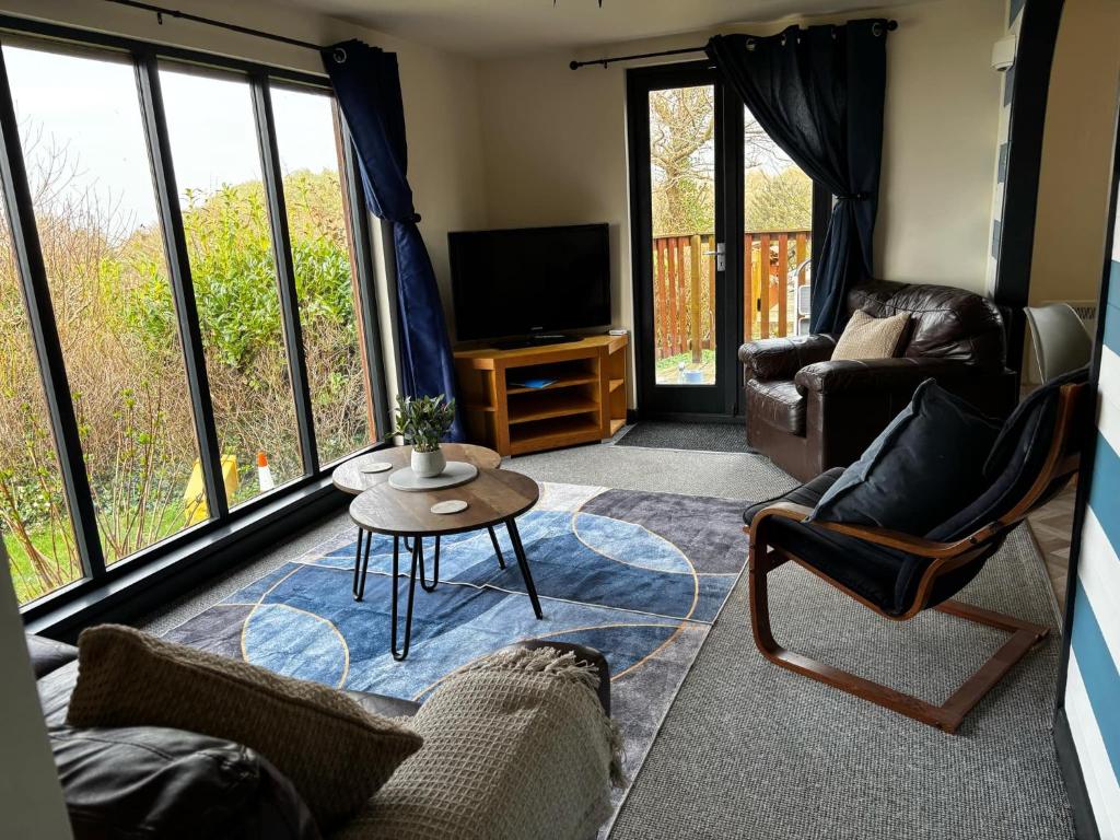 a living room with couches and a tv and windows at Northfield Holiday Park in Borth