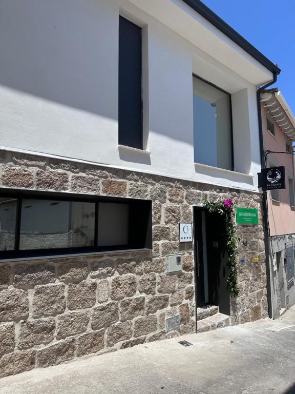 eine Steinfassade eines Gebäudes mit Fenster in der Unterkunft Casa Rural La Tajuela in Bohonal de Ibor
