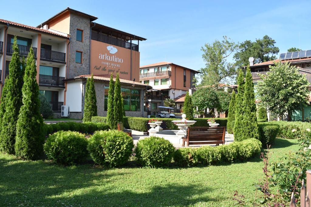 um parque com um banco e árvores em frente a um edifício em Arkutino Family Resort em Sozopol