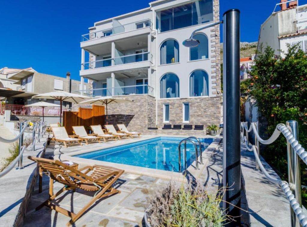 a swimming pool with chairs and a building at Apartments Villa Capitano in Mlini