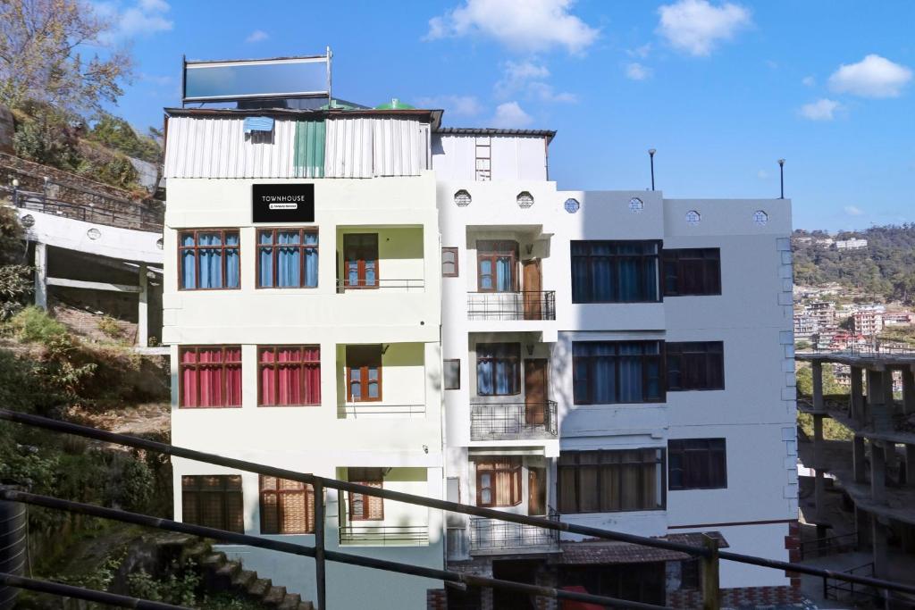 a white building with red doors and windows at Townhouse Kachighati Formerly Palm Bliss in Shimla