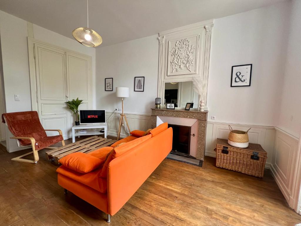 a living room with an orange couch and a fireplace at Magnifique T3 en plein centre ville de Poitiers in Poitiers