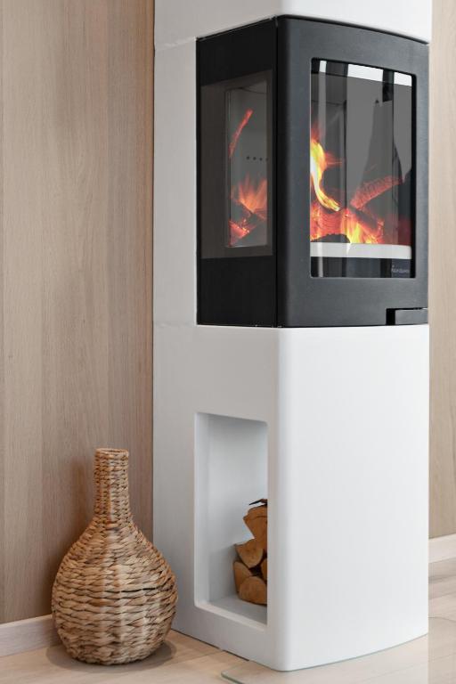 a fireplace with a tv and a vase in a room at Eksklusiv hytte i naturskjønne omgivelser, Lofoten in Storøya