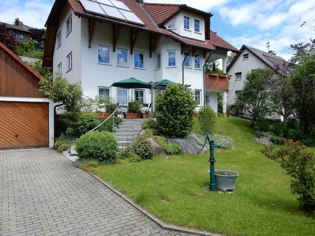 a white house with a yard with a driveway at Ferienwohnung am Wildpflanzenpark in Unterkirnach