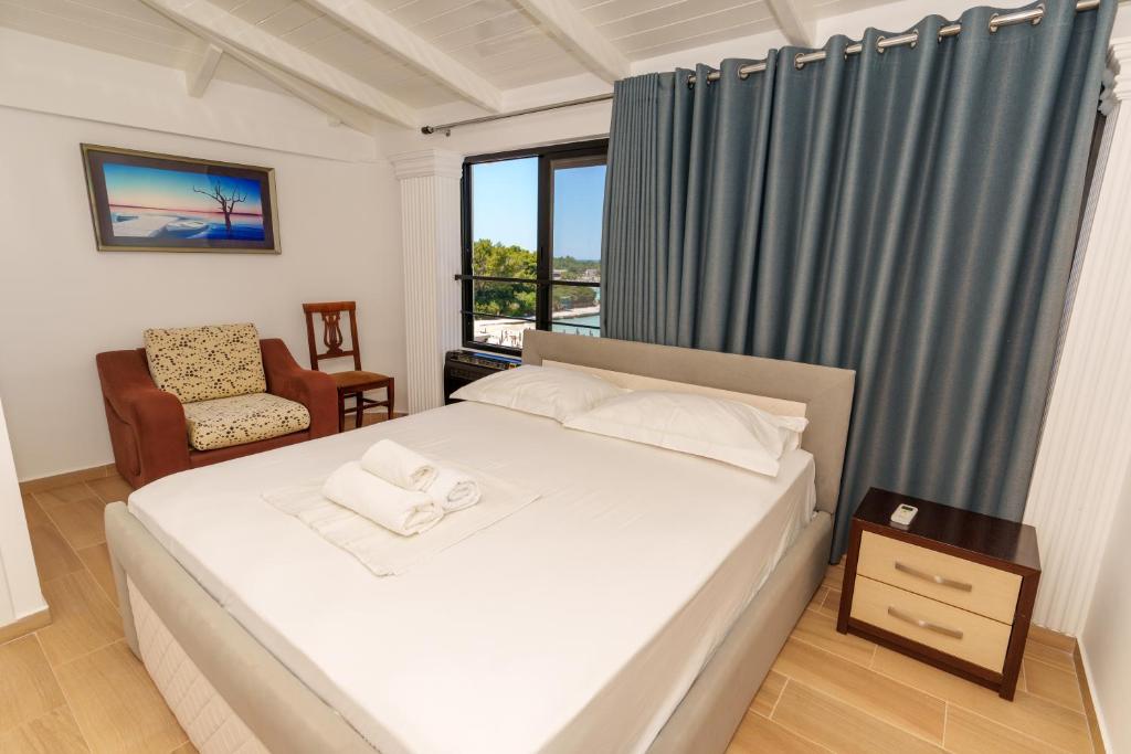 a bedroom with a bed and a chair and a window at Hotel Vila Park Bujari Ksamil in Ksamil
